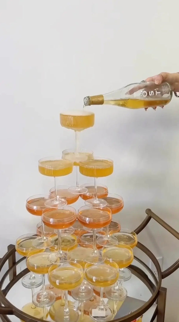 TOST sparkling drink being poured into a tower of glasses, creating a cascading effect with a white background.